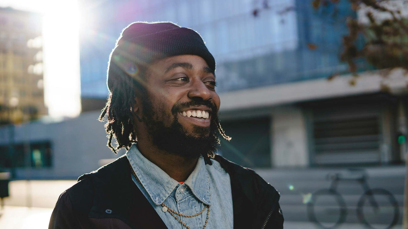 Smiling man in black coat and purple knit cap 