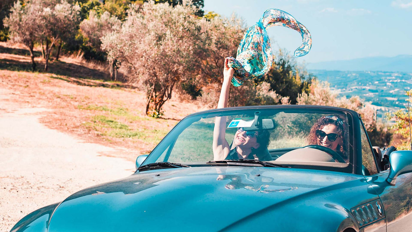 two women having fun while riding a blue car