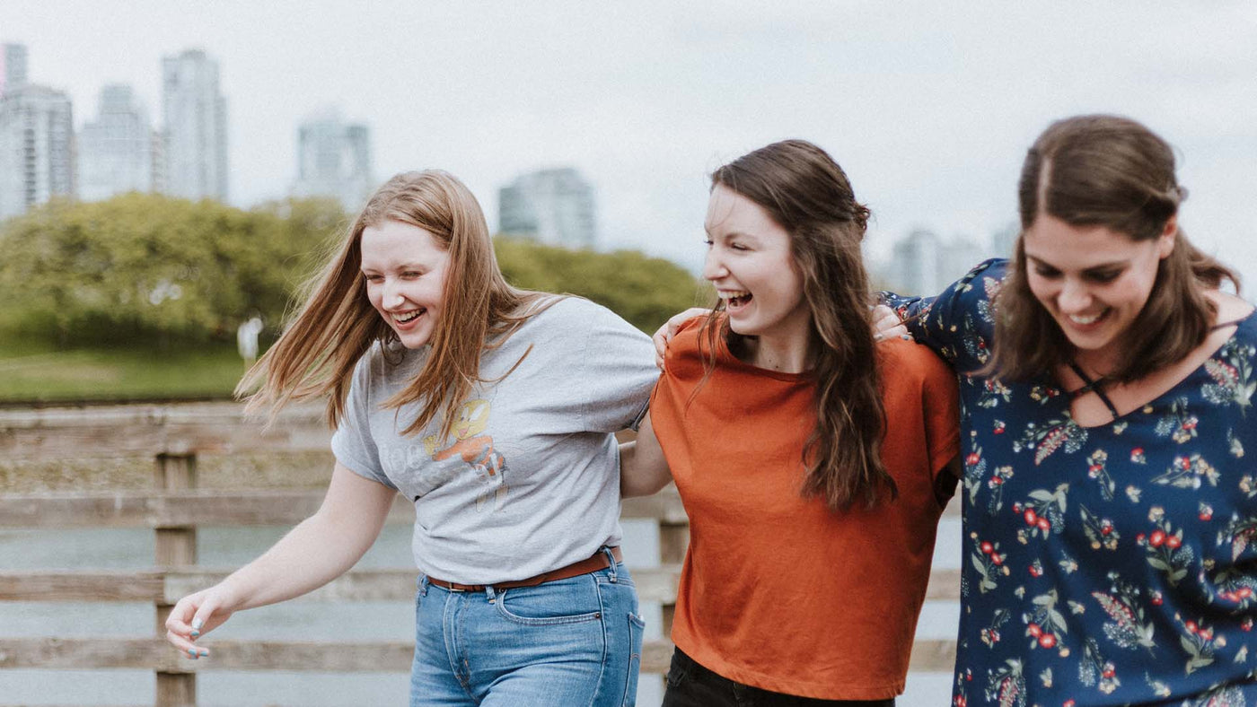 women walking and laughing with arms around each other