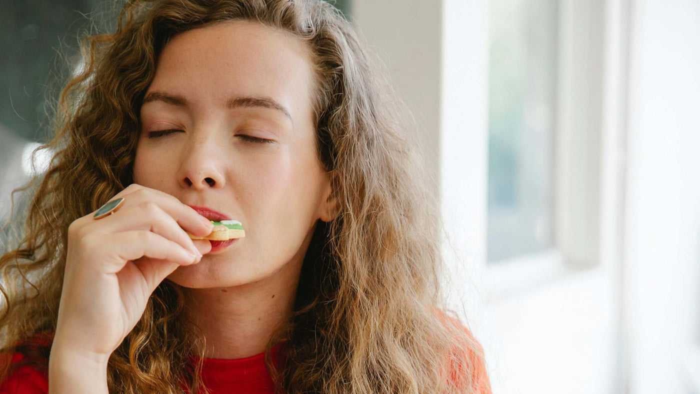 Woman biting a cookie with her eyes closed