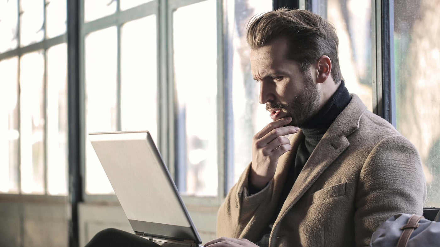 Man looking at a laptop screen with a confused expression