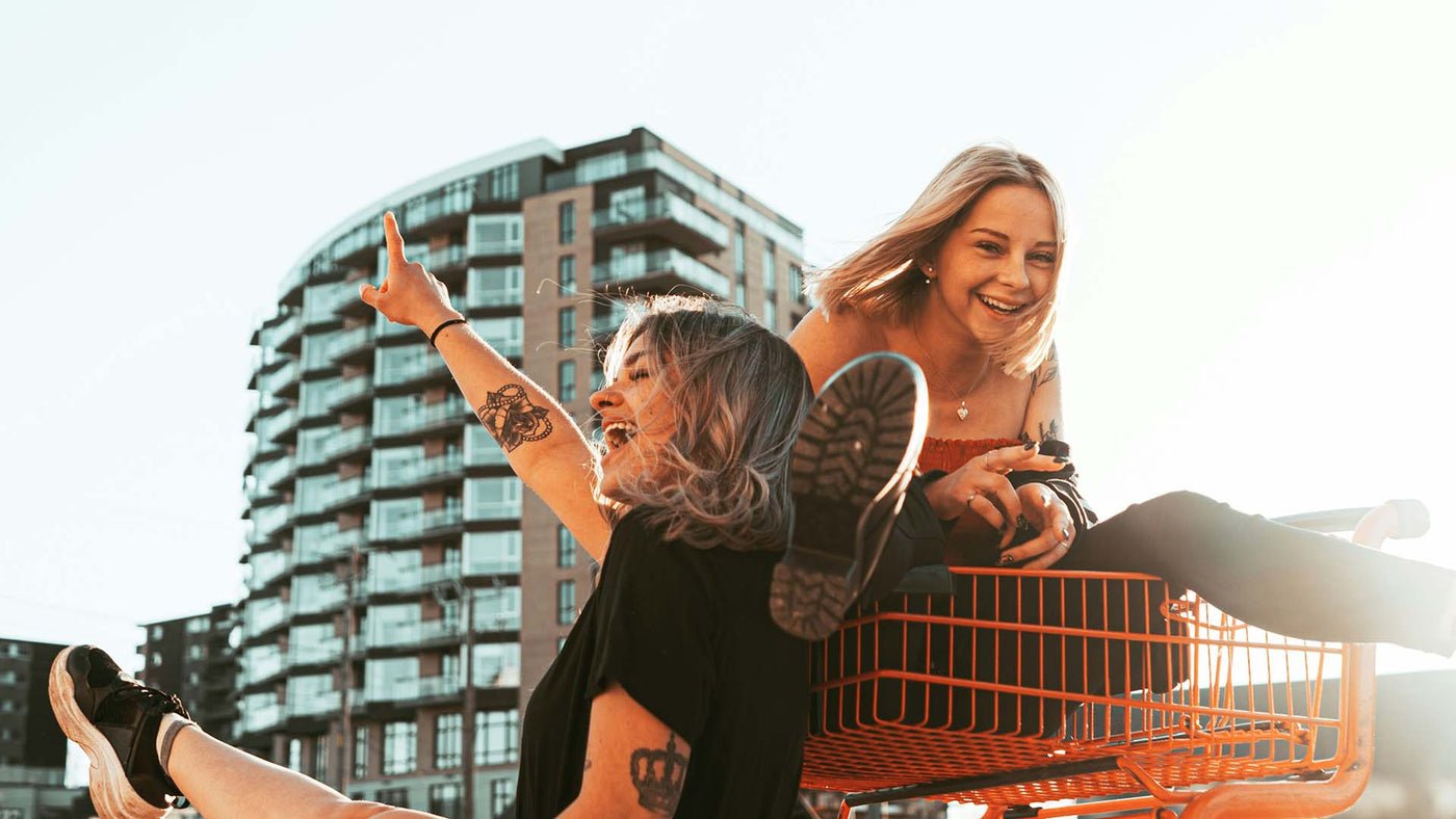 Two woman sitting in a shopping cart and laughing