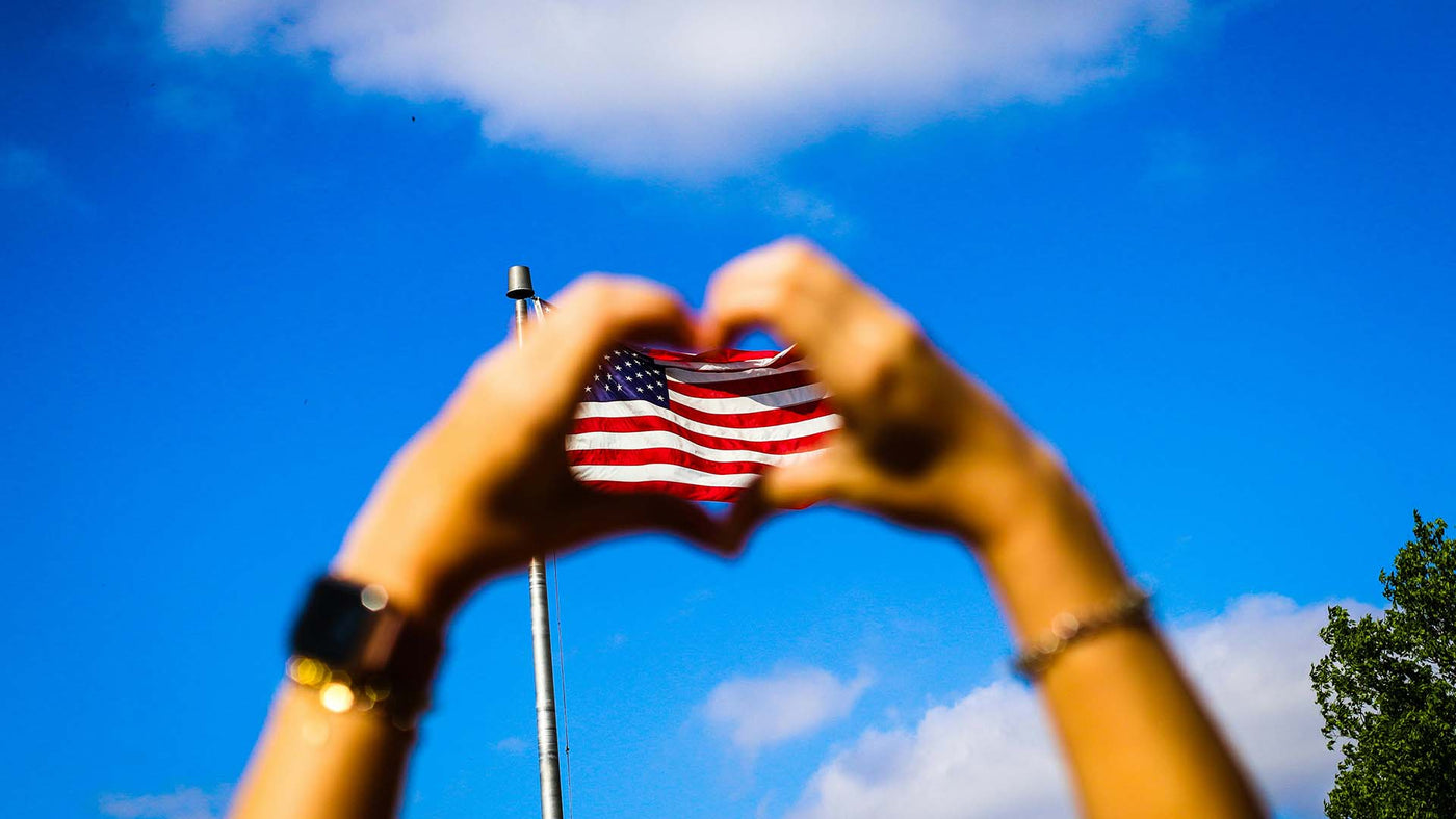 human hands formed in a heart shape and us flag in the middle
