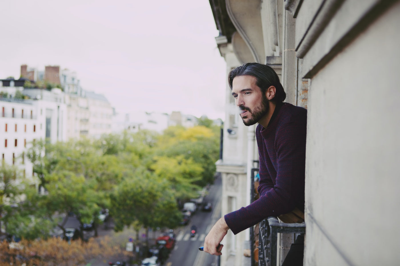 Man standing on balcony using a disposable vape device