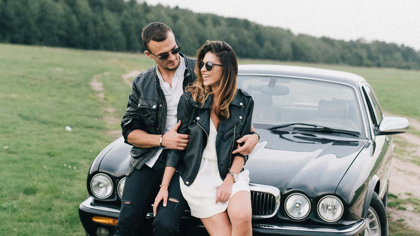 Couple leaning against an expensive car