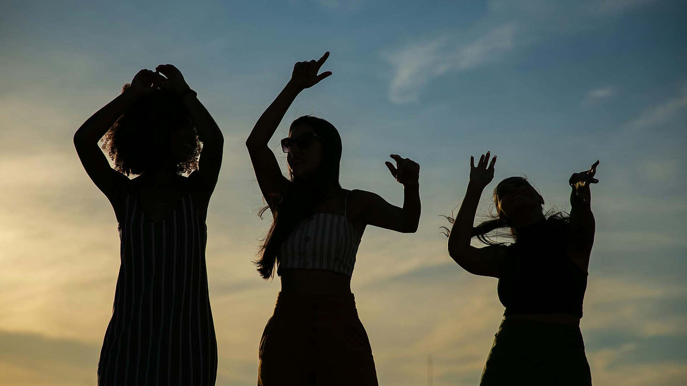 Silhouettes of people dancing at sunset