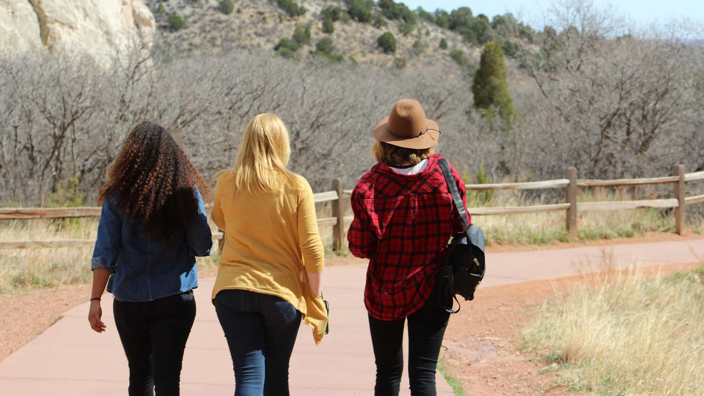 three women walking in the middle of a street during daylight