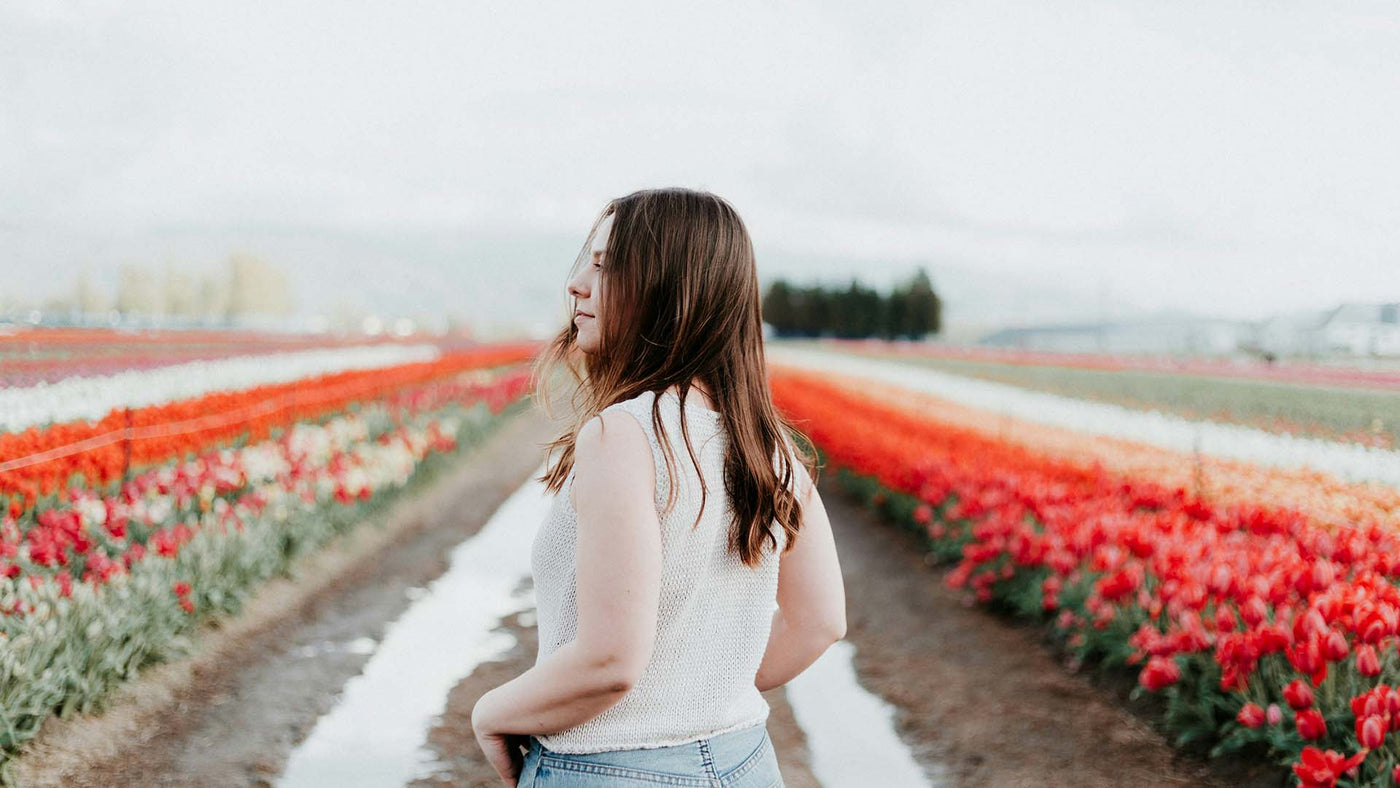 woman wearing white top standing in the tulip field
