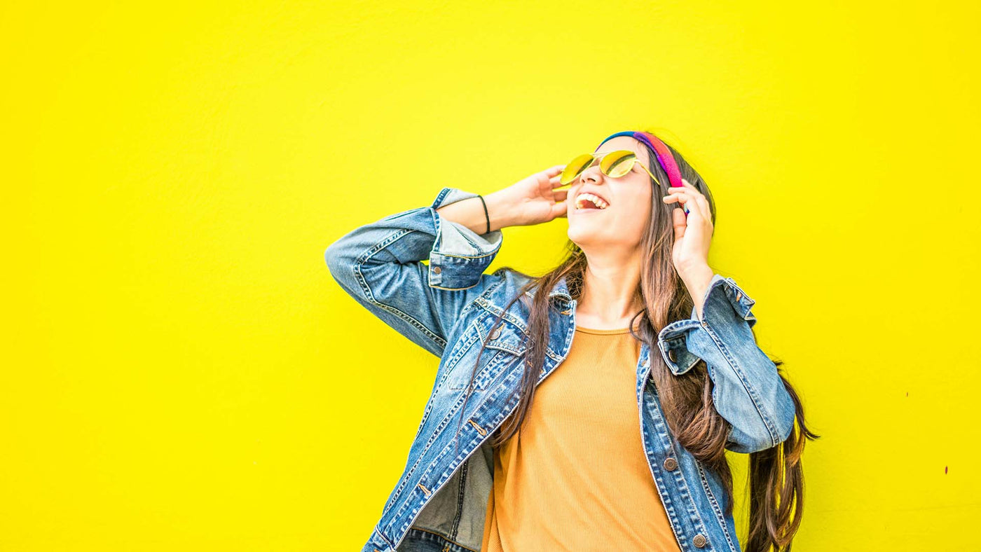 happy woman standing against yellow wall