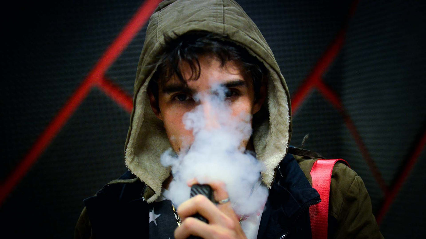 man in a hoodie blowing a vapor cloud