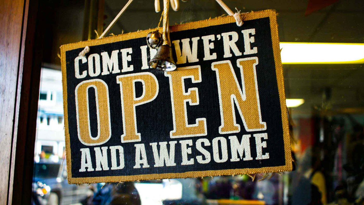 A yellow and black open store signage hanging on a storefront