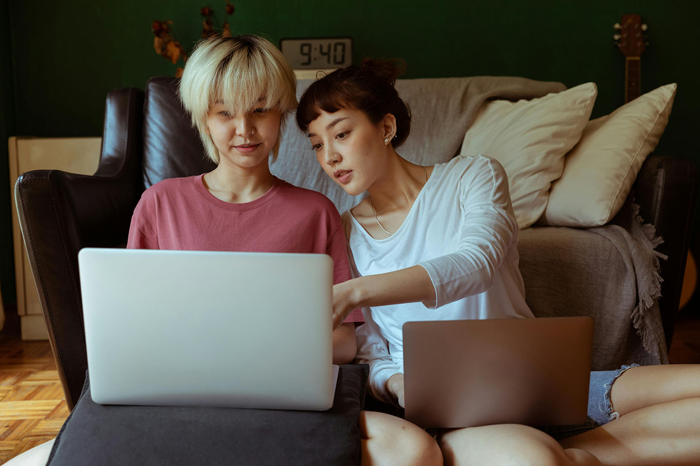 Two friends sitting on the floor with laptops